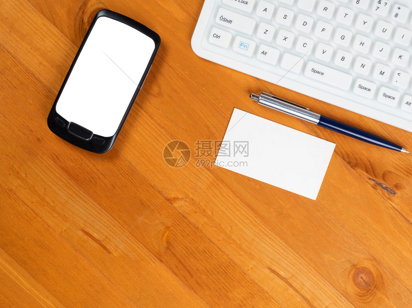 桌子房间木头带有白色键盘屏幕的智能手机和带有键盘智能电话和名片的商务服台的最顶端视图以及图片