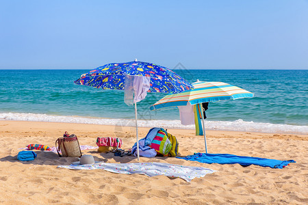 海滨阴影上两个太阳雨伞和海滩设备水边图片