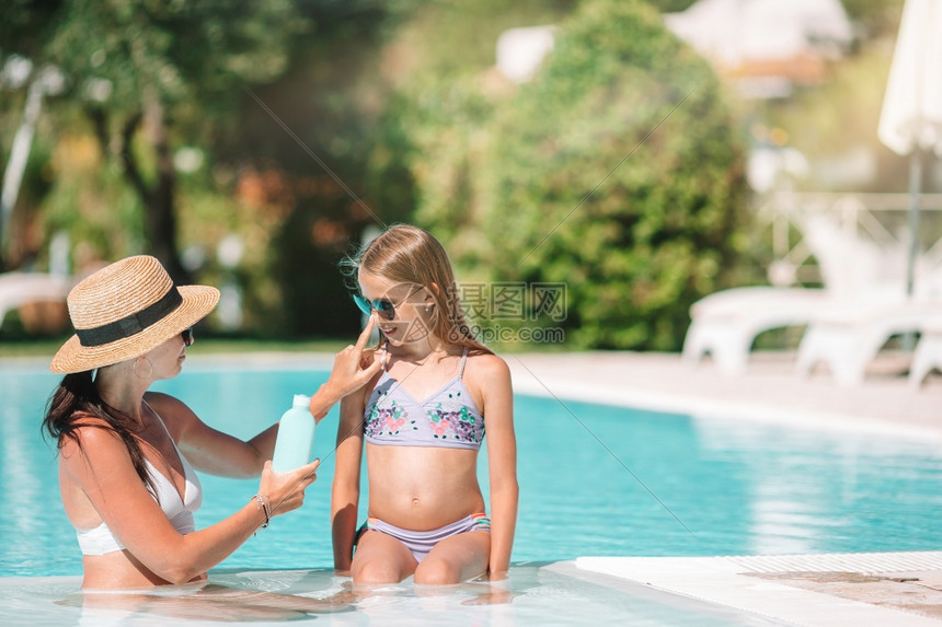 年轻妈妈在游泳池里给孩子涂防晒霜图片