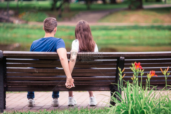 树英俊的夏天坐在公园长椅上的年轻漂亮一对夫妇在公园的长椅上坐着放松的年轻家庭在公园的长凳上图片