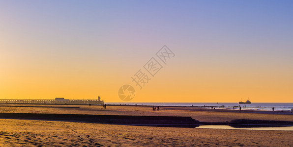 天气紫色的效果在比利时白海滨兰登堡滩日落时有灯塔和船在海上图片