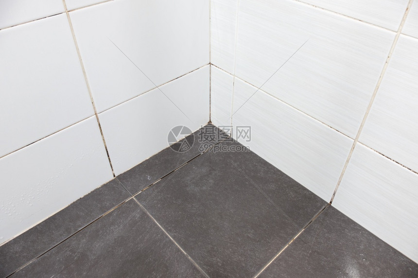 在浴室角落附近的地板砖有松散的泥浆和肮脏墙砖前视与复制空间苍白材料装饰风格图片