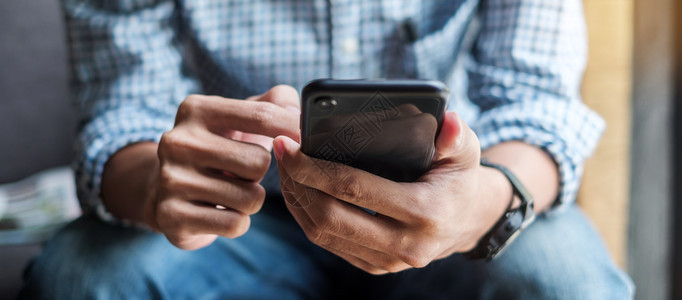 无线的屏幕持有和使用智能手机发送短讯在咖啡馆业务中打触摸屏机手的时装男生活方式技术和社交媒体网络概念的青年临时商务员持有和使用智图片