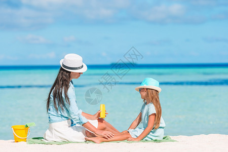 在沙滩上给孩子涂防晒霜的妈妈图片