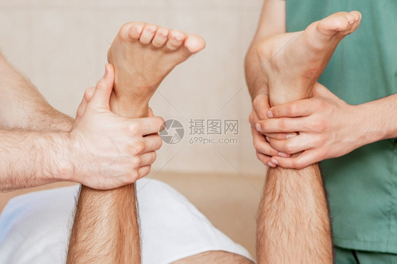 男人接受两个按摩治疗师的脚部按摩关上门的人接受腿部按摩身体福利年轻的图片