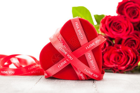 明亮的赠品盒和红玫瑰在木制桌子上的照片爱庆典图片