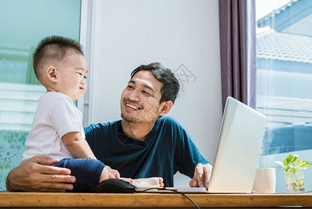 年轻的单身父亲和儿子一起使用可喜的笔记本电脑科技与生活方式概念快乐家庭与婴儿主题工作沟通图片