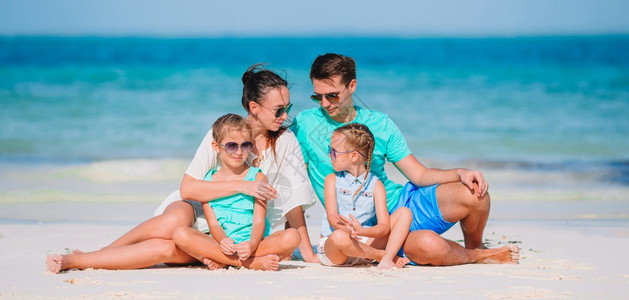 家庭海滩度假父母和孩子的肖像在海滩度假的年轻家庭青水白色的请享用图片
