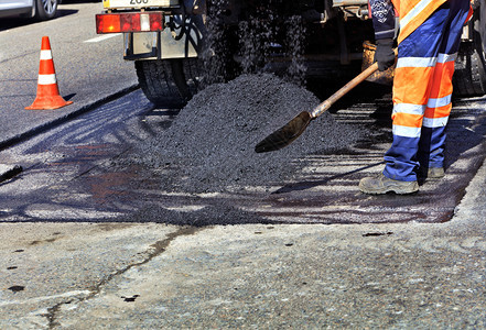 建筑工人道路作组在道路施中用新鲜沥青更部分道路并将其平整以进行修复筑路者浇注新鲜沥青并更部分道路以进行修复积极的工具图片