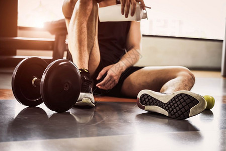 男子在健身运动和锻练中放松并持有蛋白奶昔瓶和苹果在用哑铃进行健康与人的生活方式培训后男人在健体建设运动员培训概念中可以轻松地掌握图片