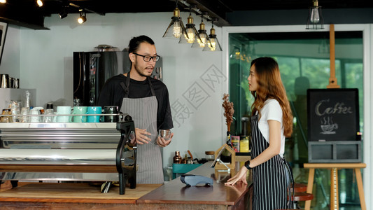 围裙自助餐厅亚洲小企业所有者快乐亚洲男子女咖啡员服务在咖啡店厅柜台的字体上说话女服务员创办新的食品和饮料业男女伙伴关系商界人士概图片