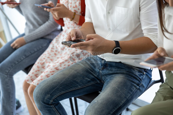 触碰网络在智能手机电子技术概念上坐在椅子检查和播放社交媒体的椅子上年轻青亚洲人无线的图片