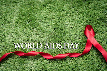 团结一致抗艾滋在绿草上的标志AIDS意识信号红丝带庆祝疾病图片