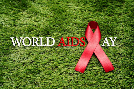 庆典抗艾滋在绿草上的标志AIDS意识信号红丝带免疫缺陷幸存者图片