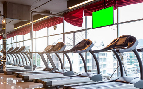 娱乐现代的体育室内健身房和康俱乐部中以空绿色白屏为引导的无重点TreadMill机和监视器与体育锻炼设备及心操运动并进行心脏锻炼图片