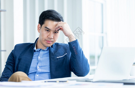 房间专业的英俊精神紧张商人从事笔记本电脑工作在商业损失后头痛在办公室背景中图片