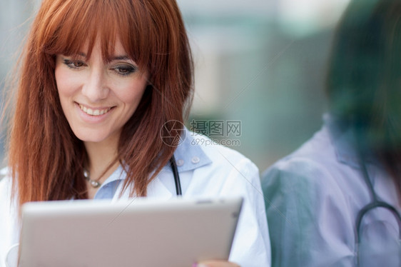 照片女医生与站在玻璃墙旁边的平板电脑Pc相片专家保持白种人图片