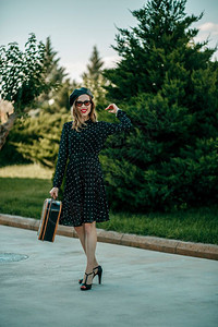 淑女身着古老黑色波尔卡圆点装饰的年轻女子手持复式提箱在外面摆放帽子时髦图片