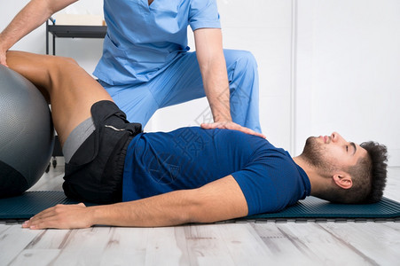 理疗师帮助男病人进行复健运动图片