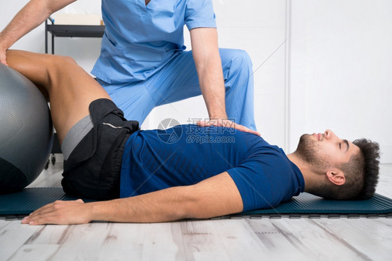 理疗师帮助男病人进行复健运动图片