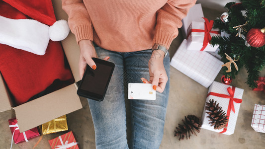 顾客正在做持有信用卡和在线购物的青年妇女新圣诞礼物购第12条手图片