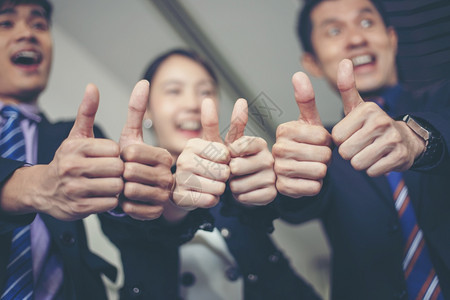 欢笑快乐的商人和女庆祝成功就拉起臂膀举大拇指来赞同提高胜利图片