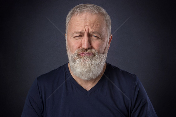 一个60岁的男子灰胡在演播室里装扮了被宠坏的红脸自信凉爽人类图片