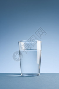 蓝色背景上一杯干净饮用水的极简主义照片带有复制空间蓝色背景上一杯干净饮用水的极简主义照片饮料凉爽的象征图片
