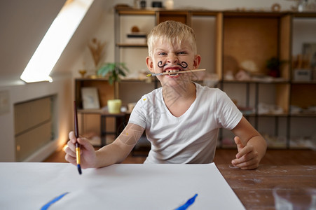 小男孩在脸上画古阿希在艺术学校习班上的孩子年轻画家愉快的爱好乐童年小男孩脸上画着古阿沙的小男孩oopicapi乐趣男生图片