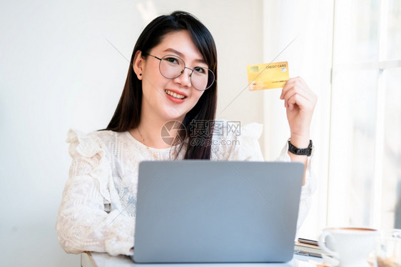 家购买在咖啡店用笔记本电脑工作的信用卡如背景网上购物和通过互联网付费等妇女临时展出的持信用卡女商人自由职业的个人商自由职者银行图片