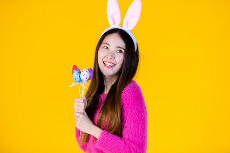 篮子假期复活节的概念快乐笑亚洲年轻女身着兔子耳朵的年轻女手拿着色彩多的复活节鸡蛋扭曲器孤立在黄色空白复制间室背景上庆典图片