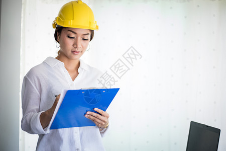 桌子团体公司的亚洲妇女工程检查作和持有蓝图的亚洲妇女在办公室中工作及持有蓝图图片