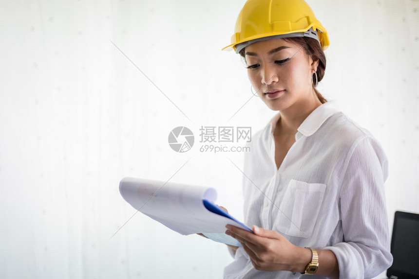 讨论男人亚洲妇女工程检查作和持有蓝图的亚洲妇女在办公室中工作及持有蓝图业的图片