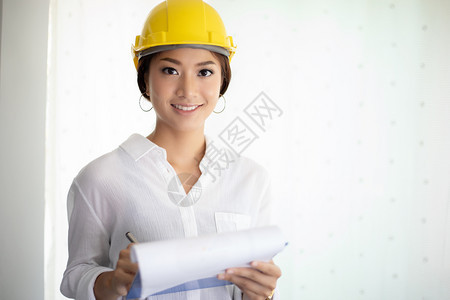 职业地点女士亚洲妇工程检查作和持有蓝图的亚洲妇女在办公室中工作及持有蓝图图片