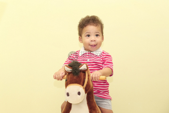 内部的一个可爱非洲男孩骑马玩具的肖像卡斯蒂略地面图片