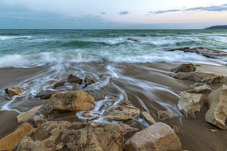 以岩石之间波浪流动的海景震撼着长期的海景云方向画图片