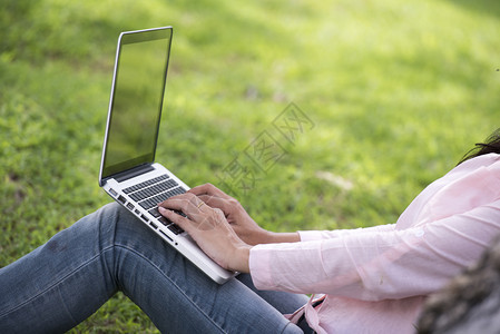 女士在公共园户外工作的年轻美女工作在膝上型笔记本室户外工作裁剪女坐在公园里用笔记本电脑工作的形象职业人图片
