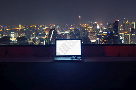 夜晚有创造力的戴在膝上型计算机空白屏幕上的眼镜夜间有城市风景工作间中断概念歇现代的图片