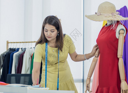 亚洲高级时装设计师正在测量曼内琴上红礼服的尺寸衣工作时尚图片