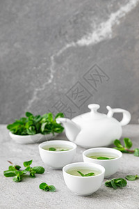 松弛正面茶壶在传统小杯子和新鲜叶中的草药薄荷茶健康的抗氧化剂饮料图片