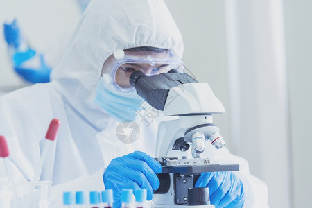 男科学家在实验室使用显微镜进行疫苗研究图片