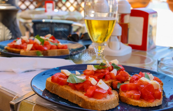 草本植物地中海烹饪餐厅三明治盘上加番茄和芝士以及轻啤酒杯开胃菜准备好的图片