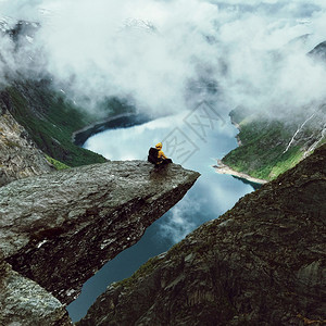 奢华户外人类坐在山前的Trolltunga尽头巡航图片