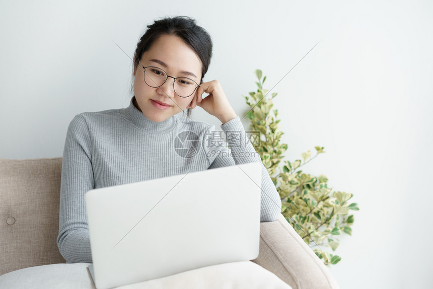 女商人亚裔妇在家里使用笔记本电脑亚洲女孩在家工作时坐着笑微肖像商业图片