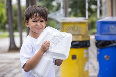 绿色盒子男孩把泡沫塑料盒放在垃圾桶里将泡沫箱装进家里的外卖食品箱中造成污染不能再使用聚苯乙烯泡沫塑料图片