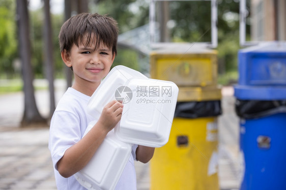 绿色盒子男孩把泡沫塑料盒放在垃圾桶里将泡沫箱装进家里的外卖食品箱中造成污染不能再使用聚苯乙烯泡沫塑料图片