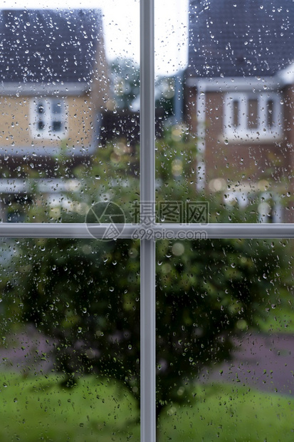 闪耀在雨天窗玻璃上有雨滴树和房子背景模糊在路面下着雨后用水滴纹理看望窗边的透过框风景细节图片