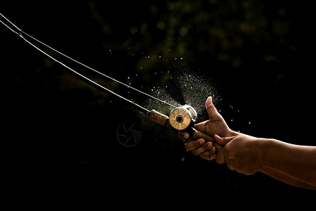 人钓鱼用黑色的底头握着手棒曲柄钩卷轴图片