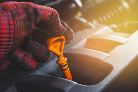 用橙色测量发动机系统油水平的械手持低压油层级计汽车维修概念用于检查发动机系统的油水平抓住关心力量图片