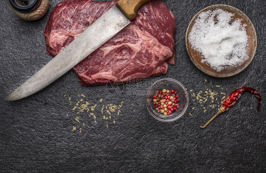 叉吃营养烹饪生牛肉排盐和胡椒雕刻刀片磨粉机的成分用深锈背景顶视面水平图片